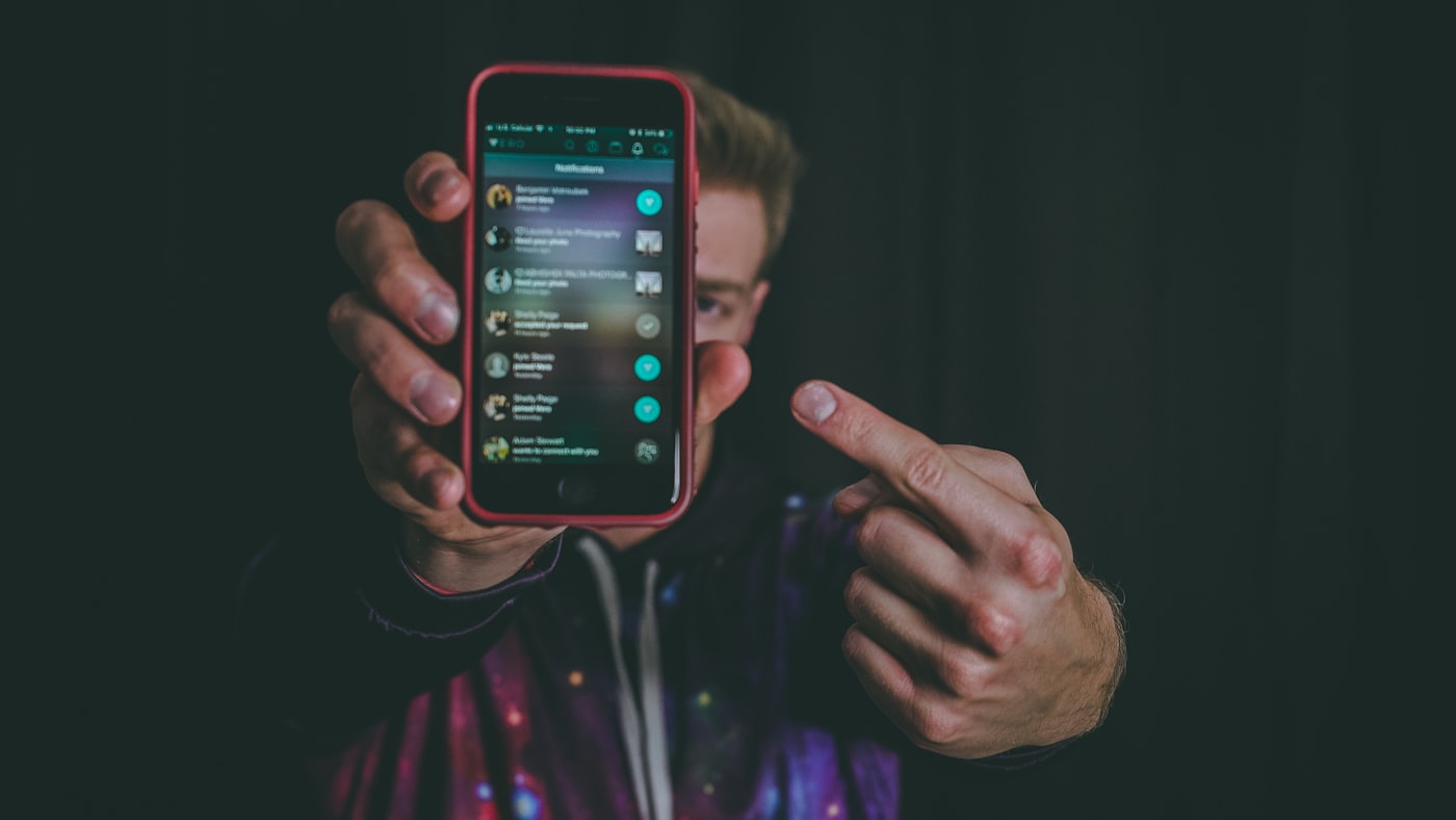 A creator holding out a phone showing their social feed notifications